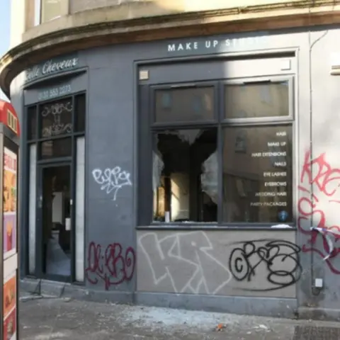Crown Office The fire-damaged Belle Cheveux salon has smashed windows and graffiti on the outside wals