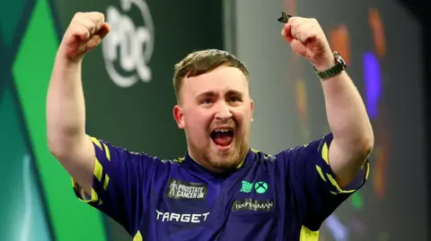 Reuters Luke Littler celebrates by raising his fists in the air after winning the 2025 PDC World Darts Championship final against Michael van Gerwen