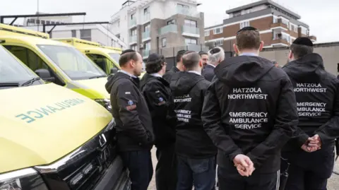 PA Media Staff from Hatzola Northwest Emergency Ambulance Service stand alongside the four replacement ambulances