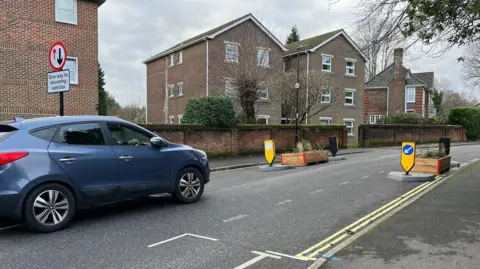 The give-way buildout on Brookvale Road. There are two wooden planters with yellow signs either side of the road that turn it into a single lane carriageway.