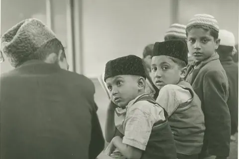 Estate of John Blakemore provided by Coventry University A group of children with various religious hats on turn to look at the camera  