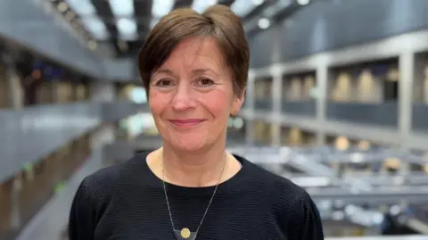 The BBC head shot a smiling woman wearing a black jumper.