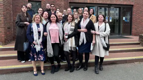 Brian Farmer/BBC A group of people gathered on the steps of Aylesbury Crown Court - a red-bricked building with black-framed entrance doors.