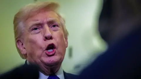Trump speaks to members of the media on board Air Force One en route to Palm Beach