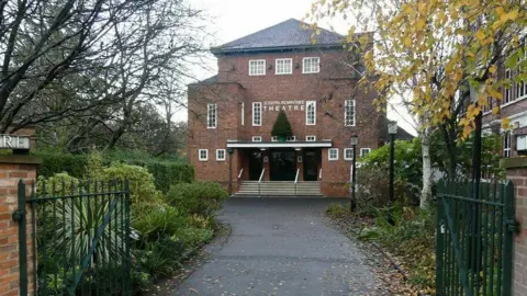 A large brick-built theatre with wide steps rising up to the main doors