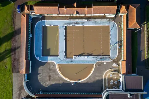 Getty Images  An aerial view of Pontypridd Lido showing the red tile of the changing rooms and the blue tiling poolside. But the water is brown. 