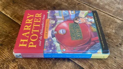 Zeldzame boekenveilingen Een eerste editie van Harry Potter en de Steen der Wijzen op een houten tafel.