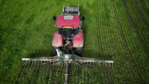 BBC A tractor spreading slurry in a field 