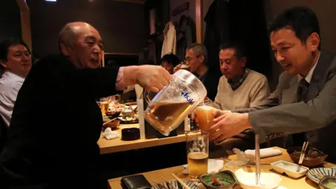 Getty Images 人们在东京一家酒吧的年终聚会上喝啤酒。