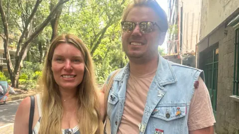 American tourists Alexis and Richard Alsomrooks smile on camera