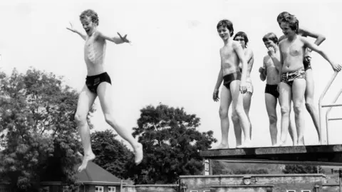 Boys jumping off diving board