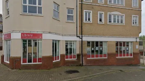 The council building is housed in a library. The picture shows three stories of the building, including a red sign on the front which says 'Library' in white writing. 