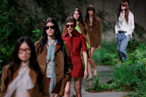 Getty Images Models on a catwalk with green plants in the background 