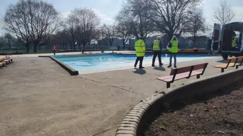 Nottingham City Council Three people in hi-vis vests looking at work progressing on the paddling pool
