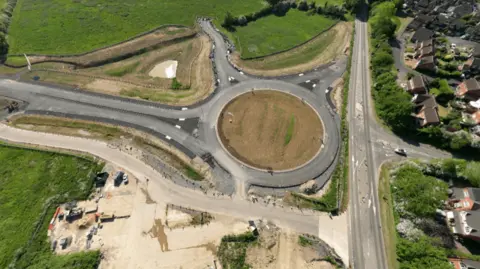 Leicestershire County Council A new roundabout in the middle with houses to the right and construction work around for a new distributor road in Melton, Leicestershire.