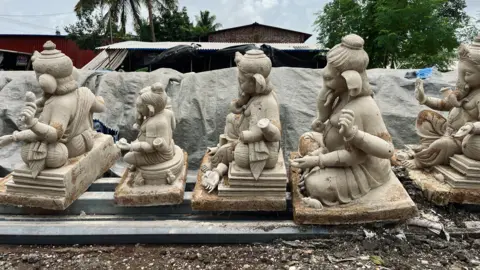 Shardul Kadam Side shot of ganpati idols kept in a straight line. They have been damaged. 