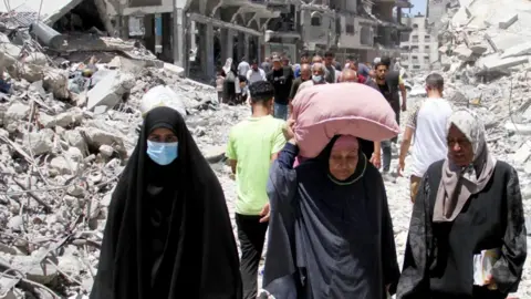 Palestinian women walk through rubble in Jabalia (file photo)