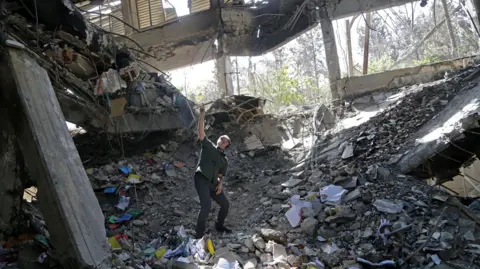 A man stands amongst the ruins of a prison building in Iran