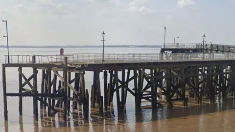 Victoria Pier on the banks of the Humber Estuary it is a wooden construction with legs embedded in the water holding up a wooden platform with metal fencing all around it