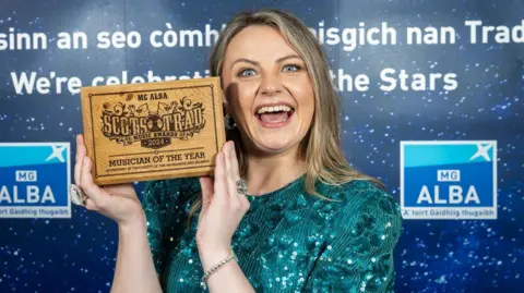 Paul Campbell Ciorstaidh has a big smile on her face as she holds up her award for musician of the year. 