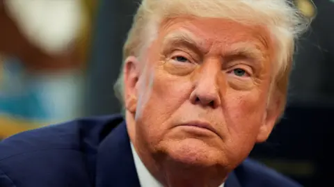 A picture of Donald Trump showing his face close up. He is wearing a blue suit