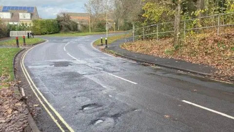 Knights Enham Junior School Huge potholes, lumps and bumps outside of a school (including Nursery School) where students and parents have to cross the road, including parents in wheelchairs. 