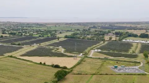 It is an aerial shot of Llanwern Solar Farm, you can see it stretch across the Levels and you can see the Severn Estuary in the background.