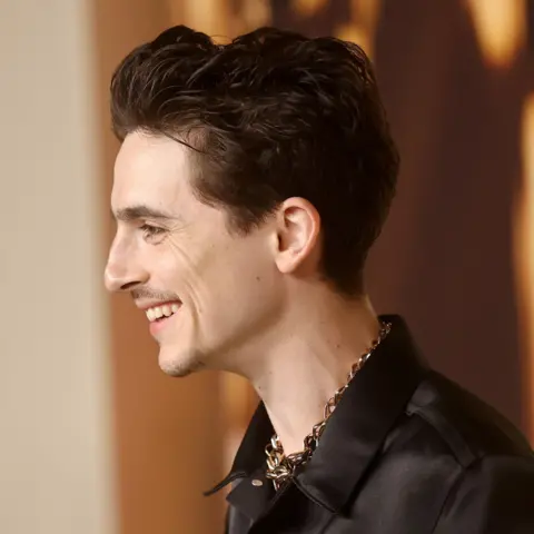 Getty Images Timothée Chalamet tersenyum dengan kemeja hitam