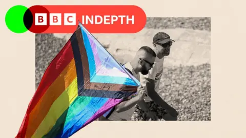 A black and white treated image of two men holding a rainbow flag