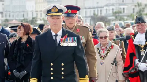 Tony Mottram Jonathan Carley is seen wearing his uniform and medals, in front of a large group of people 