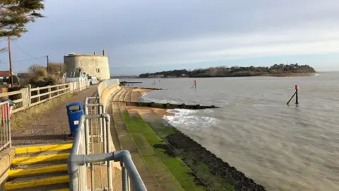 Darren Rozier/BBC The mouth of the River Deben near Felixstowe. It is high tide and steps leading down on to the beach have been covered by the water. A path along the coast can still be seen above the steps and water.