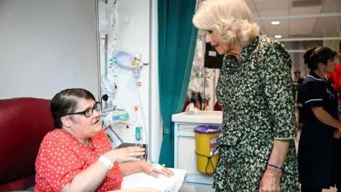 Reuters The Queen stands next to a cancer patient who is sitting while getting treatment