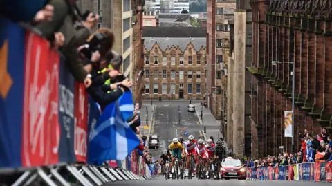 A road race, with cyclists going uphill on a Glasgow street