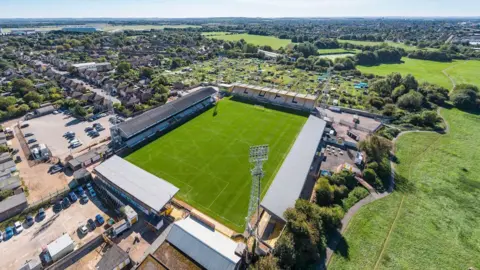 Aerial view of the Abbey Stadium with allotments in the background, houses and fields. 