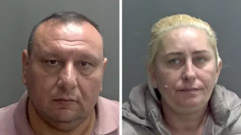 Norfolk Police Custody photos of Vadar-ghimes Agafitei and Zinca Agafitei. Vadar-ghimes Agafitei has short dark hair and is wearing a pink t-shirt, while Zinca Agafitei is wearing a grey coat and has blonde hair pulled back.