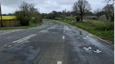 The A38 in Somerset. Diesel is on the carriageway, with a singular police car in the background.