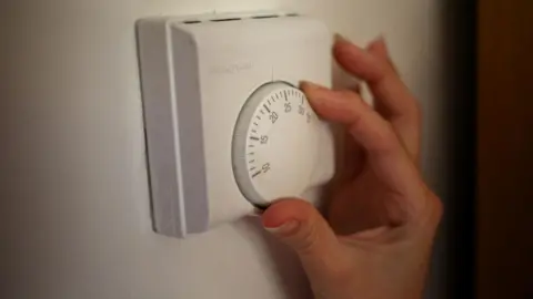 A white heating thermometer with a hand turning the dial. 