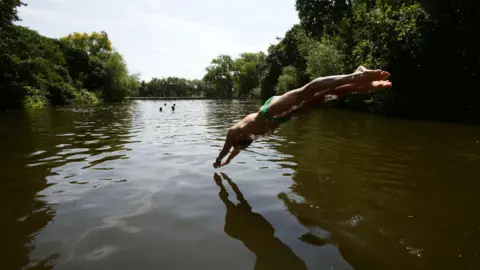 PA Media Person diving into Hampstead Heath bathing pond