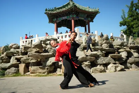 Bailarines en el parque Ritan frente a una pagoda tradicional china