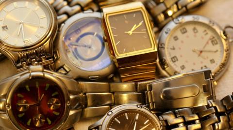 A pile of silver and gold metal watches