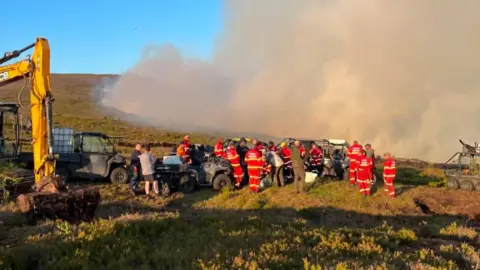 Micklehurst Cricket Club Firefighters pause during their operation at Dove Stone