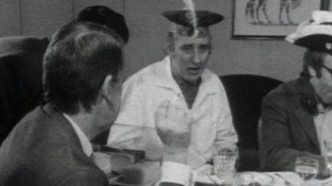 Denis Norden, Marty Feldman, Peter Sellers and Spike Milligan sit around a table.