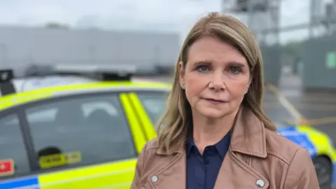 Steph Alger with a police car behind her. 