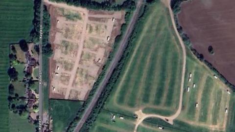 Google Maps aerial view showing a field with white rectangles, which are caravans