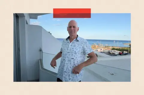Michael Carpenter wears a shirt and stands with a view in the background