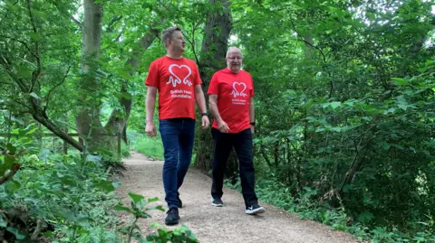 James Houghton James Houghton and his dad walk side by side on a path through the forest. Both are wearing British Heart Foundation t-shirts.