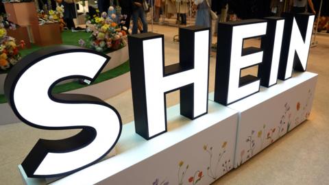 A Shein sign glows in a pop up store
