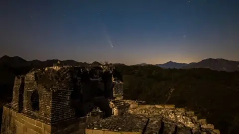   Yang Wei/VCG melalui Getty Images Komet C/2023 A3 (Tsuchinshan-ATLAS) melintasi langit di atas Tembok Besar bagian Dazhuangke yang dapat dilihat di latar depan pada malam hari pada 16 Oktober 2024 di Beijing, Tiongkok. 