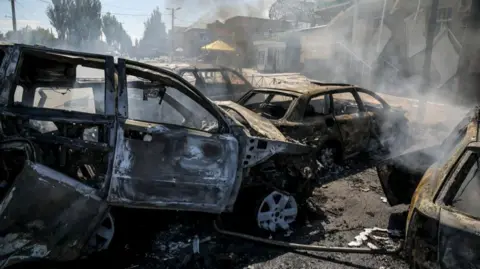 Smoke rises from burnt-out cars which are scattered across a road in Druzhkivka, in the Donetsk region of Ukraine