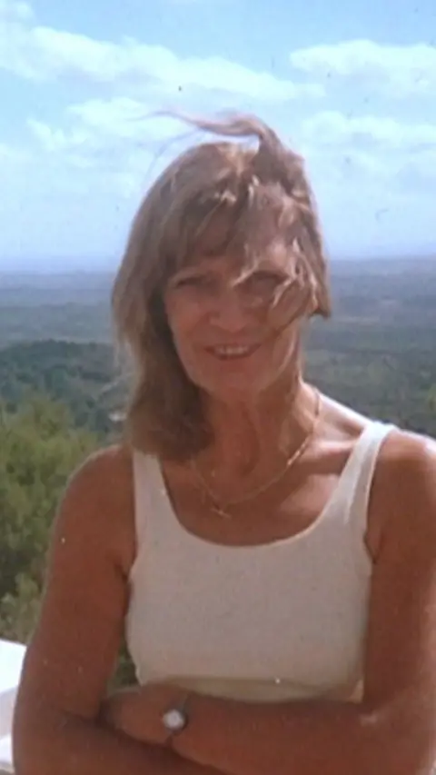 A woman with long blond hair and with sleeveless top